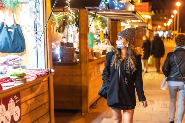 Christmas lifestyle in a new normal. Young girl with face mask visiting the Christmas market in the coronavirus pandemic