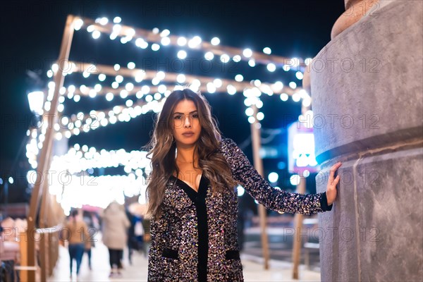 Christmas lifestyle. Portrait a young brunette Caucasian woman in a fashionable dress with sequins