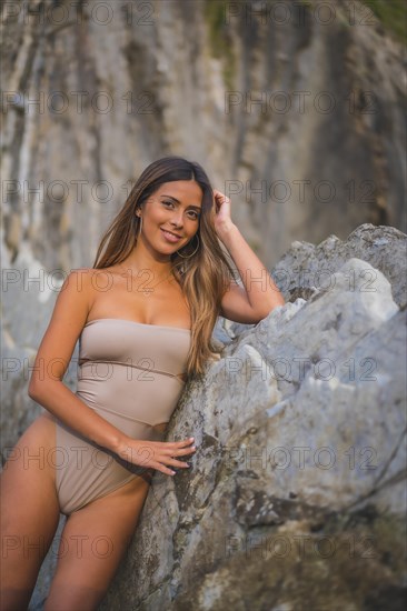 A young brunette Caucasian woman in a cream swimsuit on the Itzurrun beach in the town of Zumaia