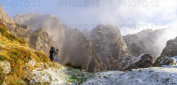 Panoramic of a photographer taking a photo with the tripod in the snowy winter sunset