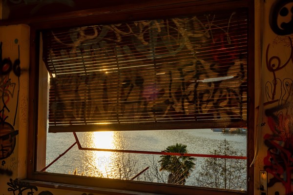 Abandoned House with Window Roller Shutter and View over Lake and with Sunlight