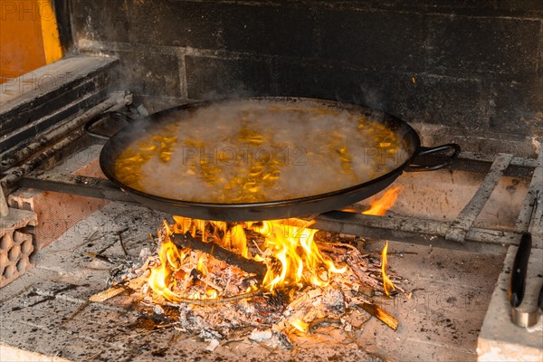 Cooking the rice of the Valencian paella with embers and vegetables. Traditional Spanish food