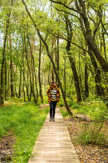 A young girl on the wooden footpath at Lake Paimpont in the Broceliande forest