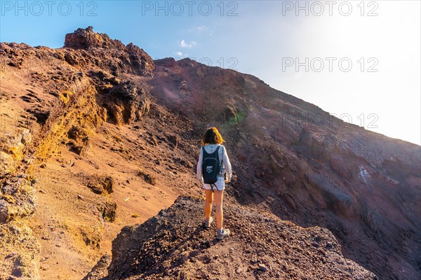 A young woman looking at the crater of the Teneguia volcano on the route of the volcanoes