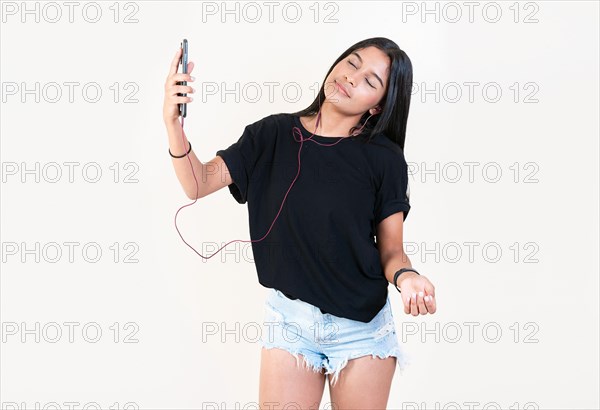 Happy latin gir listening to music with cell phone. Relaxed beautiful girl listening to music with smartphone isolated. Latin girl enjoying music with phone isolated