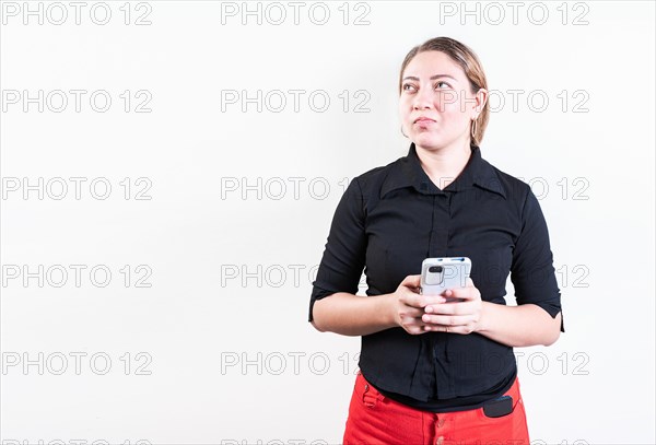 Thoughtful young woman holding phone isolated. Pensive latin girl holding smart phone on white background