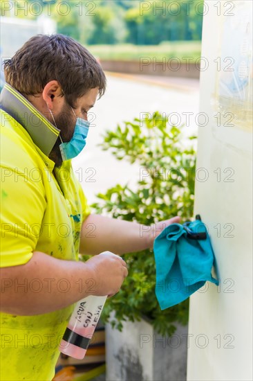 Worker in a recycling factory or clean point and garbage with a face mask and plastic protective screen