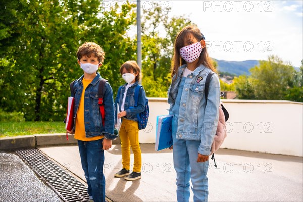 Three brothers with face masks ready to go back to school. New normality