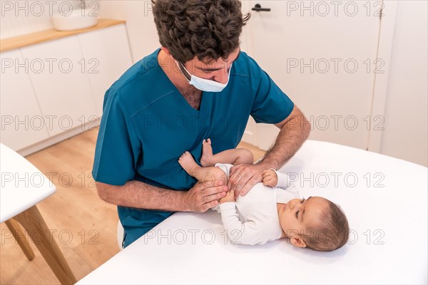 High angle view of a doctor checking up the legs of a newborn during a medical exam