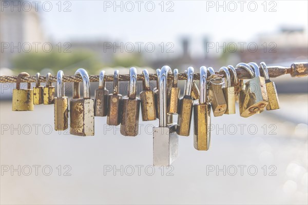 Old rusty padlocks hanging on bridge railing