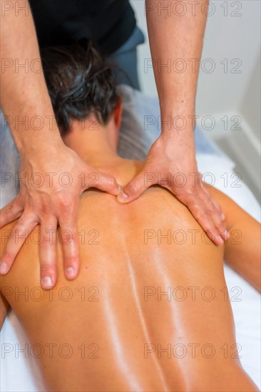 Physiotherapeutic massage to an unrecognizable woman lying on a stretcher on her back