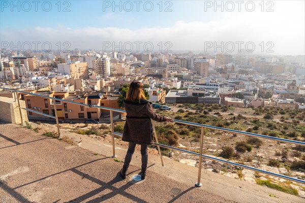 A young tourist girl looking at the city from the Cerro San Cristobal viewpoint in the city of Almeria
