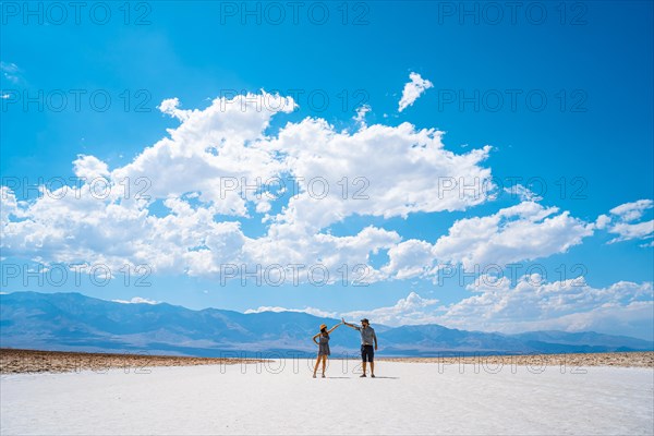 A couple of tourists walking in the white salt flat of Badwater Basin