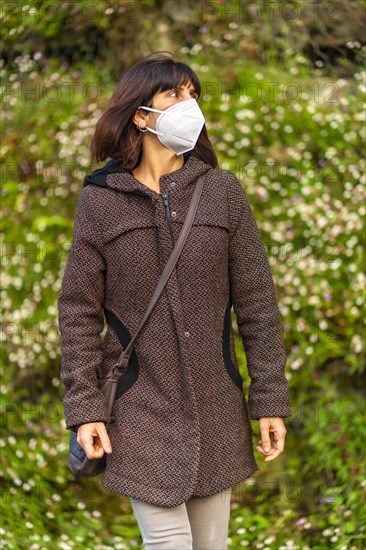 Lifestyle of a young brunette with Caucasian mask in a park. First walks of the uncontrolled Covid-19 pandemic