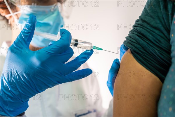 Female doctor with face mask applying the coronavirus vaccine