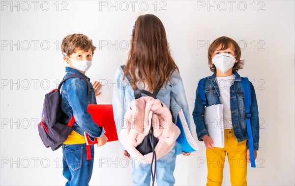 Three children with face masks ready to go back to school. New normality