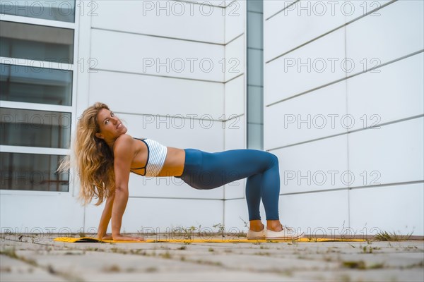 Fitness with blonde caucasian girl exercising on a yellow mat with white wall in the background