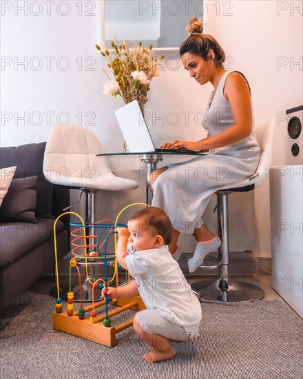Young Caucasian mother caring for her young son and teleworking