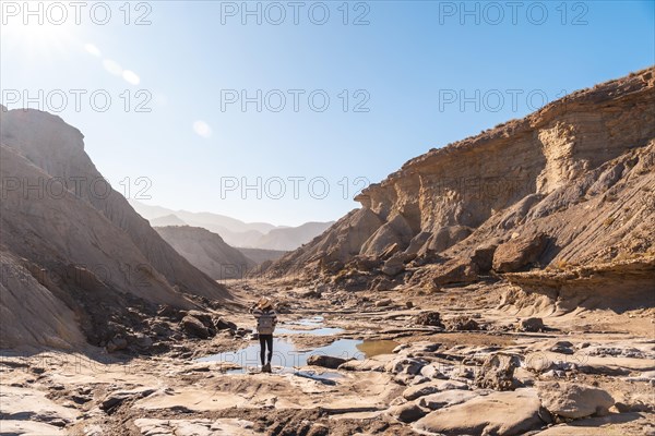 A young woman walking along the water in the desert on a trek in the Travertino waterfall and Rambla de Otero in the desert of Tabernas