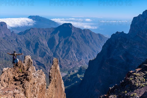 A young man after finishing the trek at the top of the volcano of Caldera de Taburiente near Roque de los Muchachos looking at the incredible landscape