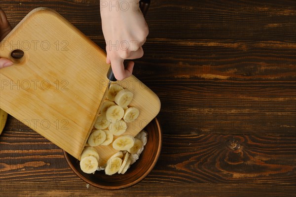 Dropping slices of banana into a bowl with cottage cheese