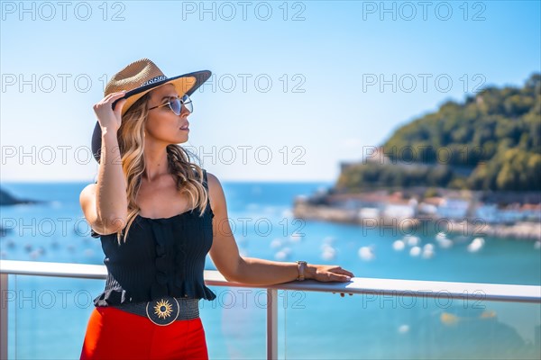 Blonde woman in a luxury hotel on a terrace wearing a hat with glasses in the city of San Sebastian
