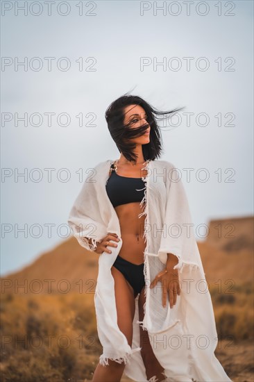Brunette Caucasian model in a white dress and a black bikini in the Bardenas Reales desert