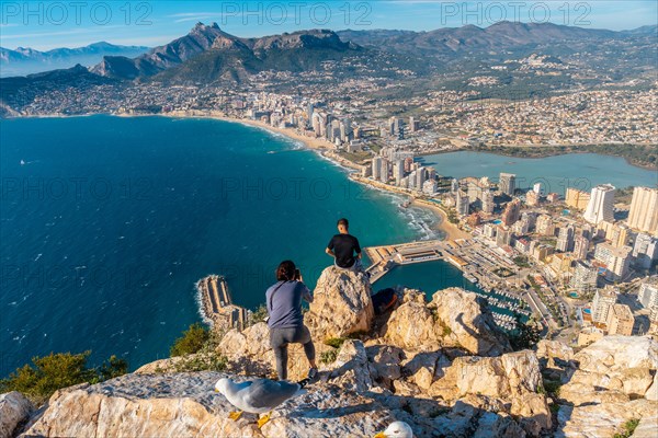 A young man photographed sitting on top of the Penon de Ifach Natural Park in Calpe