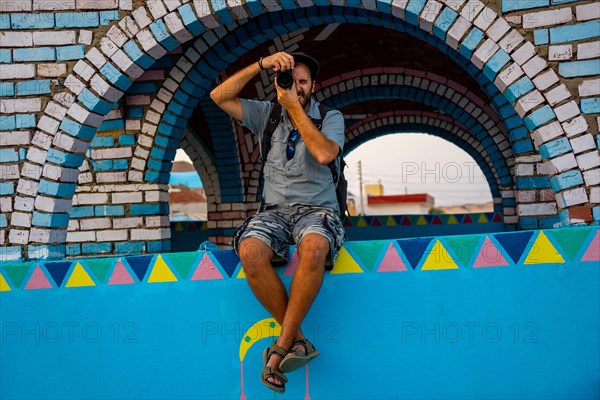 A young tourist sitting on a beautiful terrace of a traditional blue house in a Nubian village along the Nile river and near the city of Aswan. Egypt