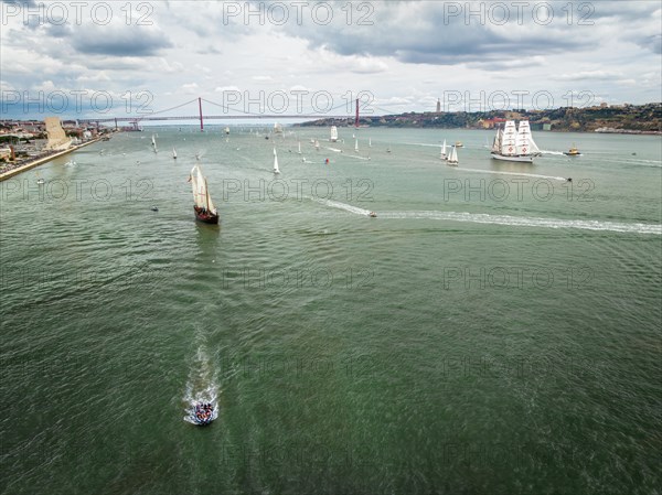 Aerial drone view of tall ships with sails sailing in Tagus river towards the Atlantic ocean in Lisbon