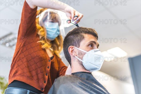 Hairdressers after the Coronavirus pandemic. Hairdresser with face mask and protective screen