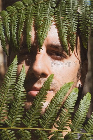 A young man inside ferns in nature in summer. Listorreta Natural Park in the town of Errenteria in the Penas de Aya or Aiako Harria park. Gipuzkoa