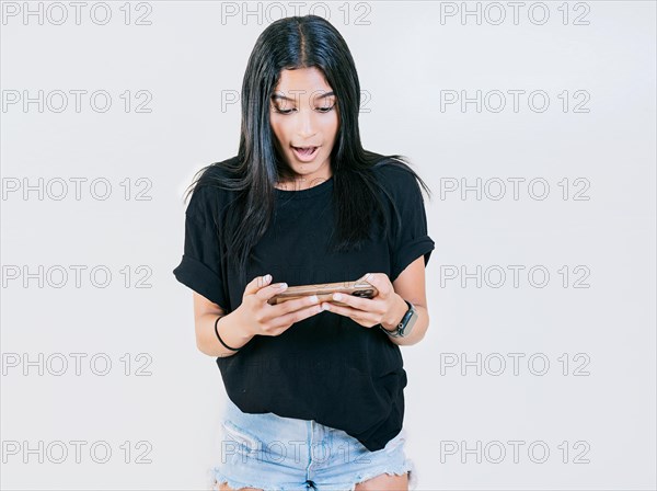 Happy teen girl using and looking phone isolated. Cheerful young girl looking at a promotion on the phone isolated