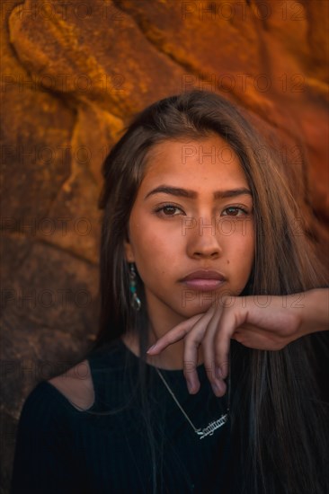 A young pretty brunette Latina with long straight hair in a short black T-shirt and pink pants. Portrait of the girl in a close-up shot