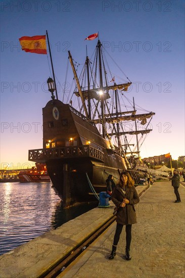 A tourist visiting the old ship at sunset on the promenade of Muelle Uno in the Malagaport of the city of Malaga