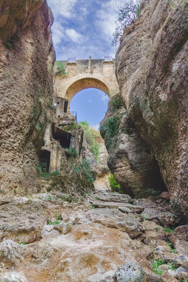 Stone bridge over a cliff with a dry riverbed running underneath. in ronda
