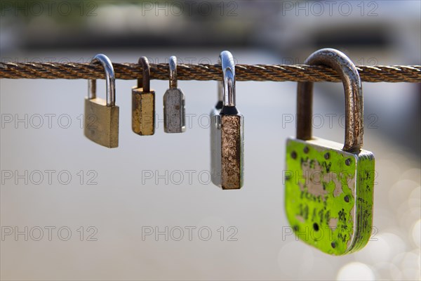 Old rusty padlocks hanging on bridge railing