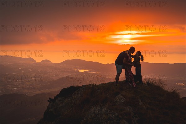 Parents with their son on top of a mountain at sunset
