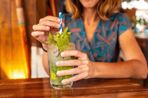 Young girl refreshing herself in the summer with a Mojito cocktail on vacation in a beach bar