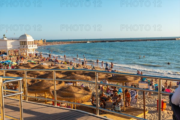 Bathers on the beach of La Caleta in the summer sunset of the city of Cadiz. Andalusia