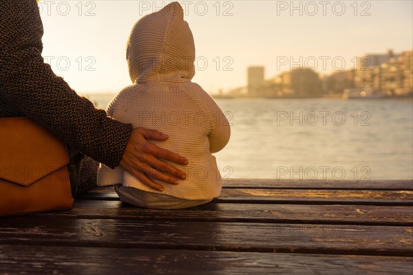 Detail the hand of a mother with her baby at sunset on Playa del Cura in the coastal city of Torrevieja
