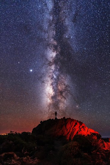 Silhouette of a young man under the stars looking at the lactea way of the Caldera de Taburiente near the Roque de los Muchahos on the island of La Palma