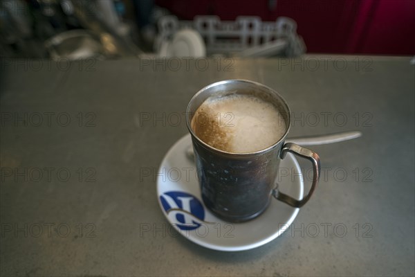 Cappuccino in a tin cup in a small bistro