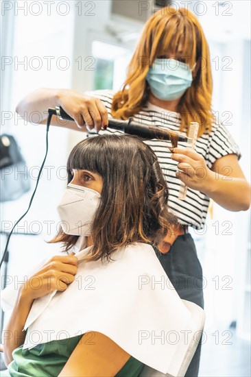 Hairdresser with mask and client