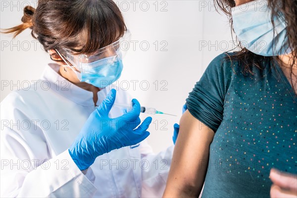 A woman doctor with a face mask applying the coronavirus vaccine