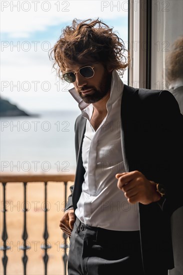 Street style with a young dark-haired caucasian man in a black suit and a white shirt in a luxurious hotel