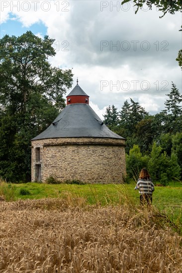 A young girl next to the thatched barn in French Brittany in the summer of July