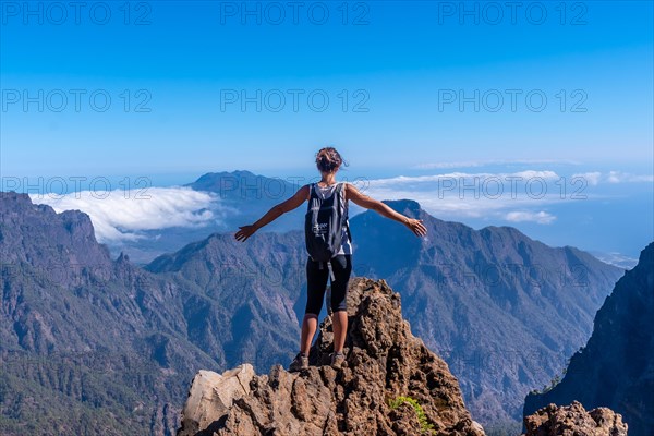 A young woman looking out from the top of the Caldera de Taburiente volcano near Roque de los Muchachos one summer afternoon