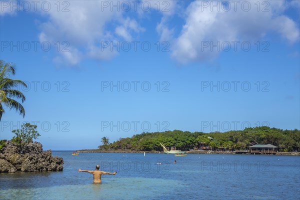 A young man entering the Caribbean Sea at West End Beach on Roatan Island. Honduras