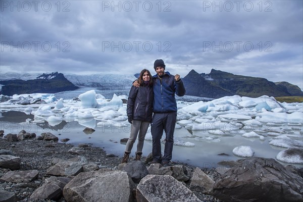 A couple with a backpack looking at the Jokulsarlon Ice Lake in the golden circle of southern Iceland